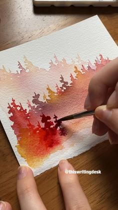 someone is painting with watercolors on paper