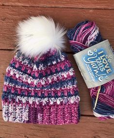 a crocheted hat with a ball of yarn next to it on a wooden surface