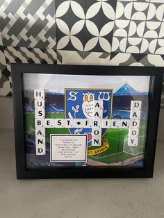 a framed scrabble art piece with words written on it in front of a patterned wall