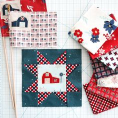 several quilts are laid out on a table with some sewing needles and fabric pieces