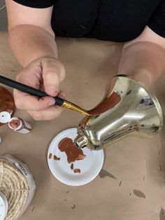 a person pouring chocolate onto a white plate with gold trimmings on the edge