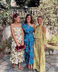 three women standing next to each other in dresses