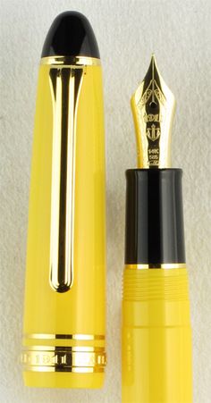 a yellow and black pen sitting next to each other on a white surface with gold trim