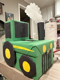 a green tractor made out of cardboard sitting on top of a counter