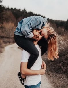 a man carrying a woman across a dirt road