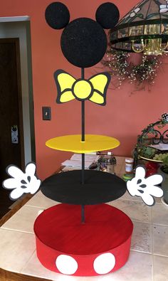 three tiered mickey mouse cake stand in the shape of a minnie mouse with yellow and black ears