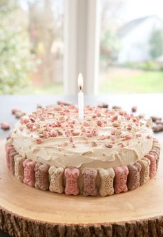 a birthday cake with white frosting and pink sprinkles on a wooden table