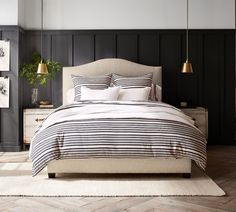 a bedroom with black and white striped bedding, two lamps and a rug on the floor