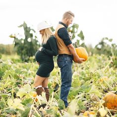 a man and woman holding pumpkins in a field