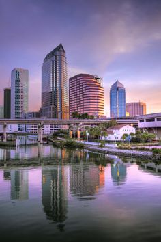 the city skyline is reflected in the still water of the river that runs through it