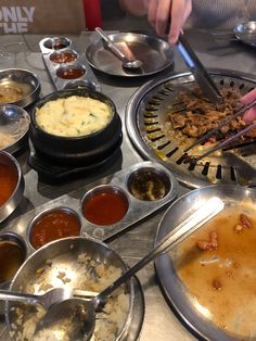 a table filled with lots of different types of food on top of metal pans