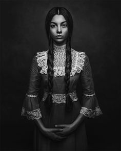 a black and white photo of a woman with long hair wearing an old fashioned dress