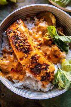 a bowl filled with rice and meat covered in sauce