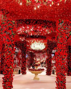 an elaborately decorated walkway with red flowers on the ceiling and chandeliers hanging from the ceiling