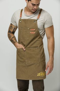 a man wearing an apron with tattoos on his arm and hands behind his back, looking down