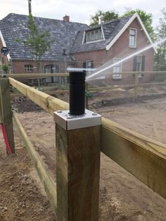 a wooden fence with a water sprinkler attached to the top of it