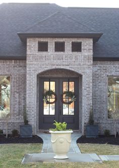 a large white potted plant sitting in front of a brick house with black doors