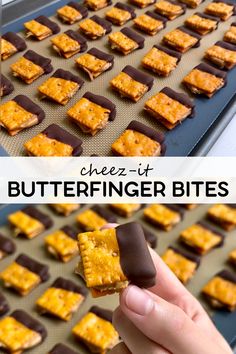 a hand holding a piece of butterfingerer bites in front of a baking sheet