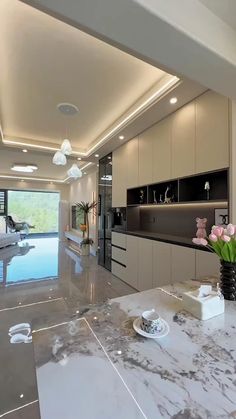 a large kitchen with marble counter tops and white cabinets next to a living room filled with furniture