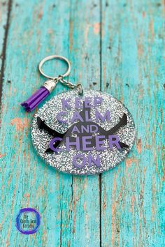 a purple and black keychain with the words keep calm and cheer on it