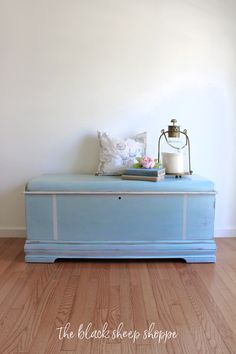 a blue bench sitting on top of a hard wood floor next to a white wall