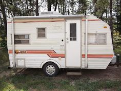 an rv parked in the woods near some trees