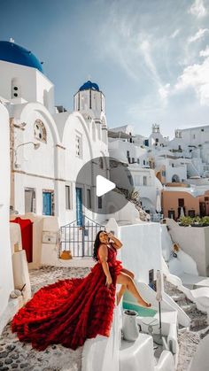 a woman in a red dress sitting on a white building