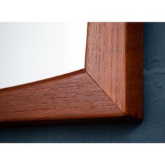 the corner of a wooden shelf against a blue wall with wood graining on it