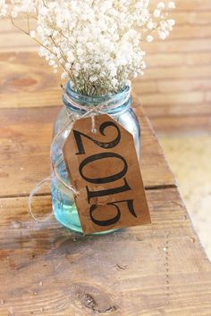 a small jar filled with baby's breath sitting on top of a wooden table