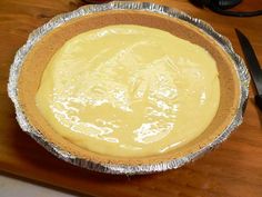 a pie crust in tin foil sitting on top of a wooden table