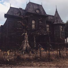 an old house with a tree growing out of it's front yard and fence