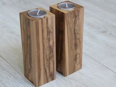 two wooden candlesticks sitting on top of a white wood floor next to each other