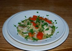 a white plate topped with rice and vegetables on top of a wooden table next to a fork