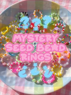 a white plate topped with lots of colorful beaded beads next to a pink sign that says mystery seed bed rings