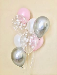 a bunch of balloons that are sitting on a table in front of a wall with snowflakes