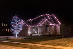 a house is decorated with christmas lights in the front yard and trees on the lawn