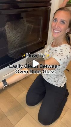 a woman sitting on the floor in front of an oven and pointing at it with her hand