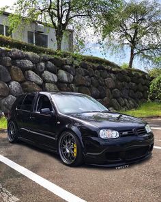 a black car parked in front of a stone wall