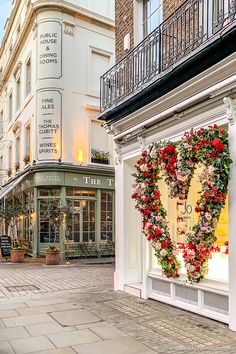 a heart shaped wreath is on display in front of a storefront with stairs leading up to the second floor