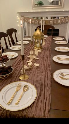 the table is set with gold and white plates, silverware, and candlesticks