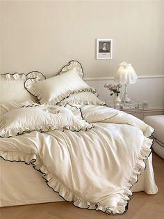 a bed with white sheets and black ruffles in a room next to a window