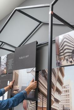 a man is looking at pictures on the wall in front of him and pointing to them