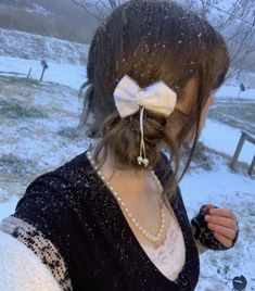 a woman with a white bow in her hair and pearls on her head is standing in the snow