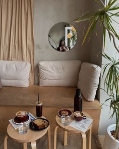 two small tables with food on them in front of a mirror and couch behind it