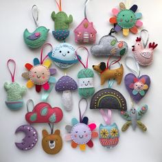 a collection of handmade felt ornaments hanging from hooks on a white wall in the shape of houses and animals