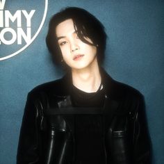 a woman in black leather jacket standing next to a blue wall with the jimmy lion logo on it