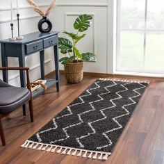 a black and white rug with tassels on the floor next to a chair