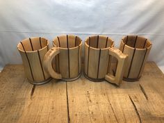 four wooden mugs sitting on top of a wooden table