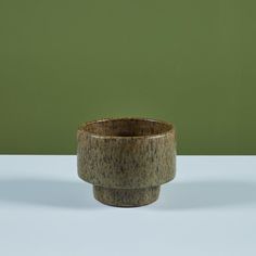 a wooden bowl sitting on top of a white table next to a green wall in the background