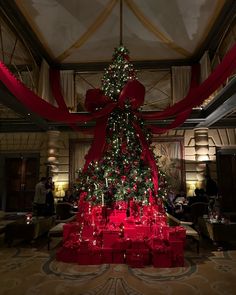 a large christmas tree with red presents under it